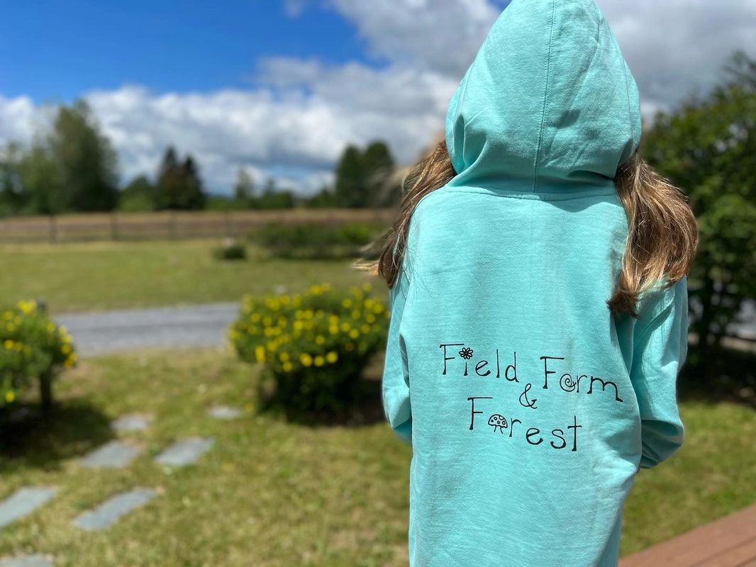A child wearing a Field, Farm & Forest hoodie