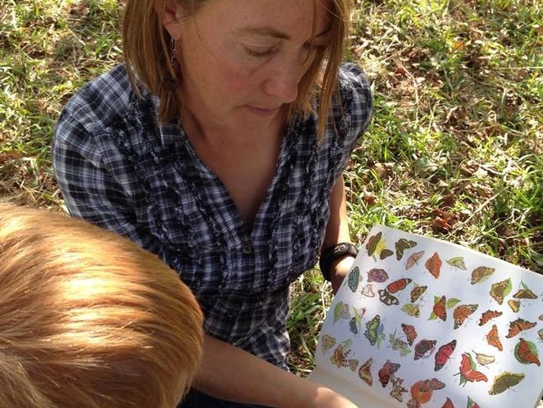 Jessica Simpson examining a butterfly guide outdoors with a child